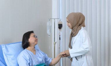 Hastanede yaşlı bir hastanın elini tutan Müslüman kadın doktor, özen ve neşe dolu bir konseptle ilgileniyor..