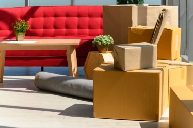 Karton kutular istiflenmiş, bitkiler, yeni evdeki modern oturma odasının büyük penceresinin yanındaki rahat kanepe, yeni ev kavramına taşınmayı kutluyorlar, insanlar yok.