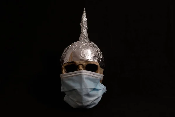 skull wearing surgical mask and a tinfoil hat isolated , black background