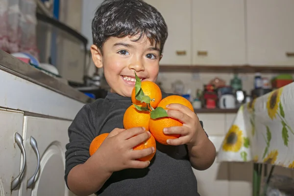 Mutfakta kollarında portakal olan 3 yaşında bir çocuk.