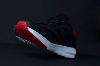 Siyah arka planda siyah spor ayakkabılar.