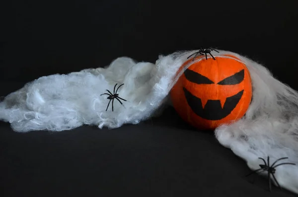 Happy Halloween pumpkin on the web with spiders.