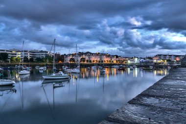 Mavi saatte Dun Laoghaire limanı. Batı İskelesi. Dublin, İrlanda 'daki ünlü limanın akşam çekimleri