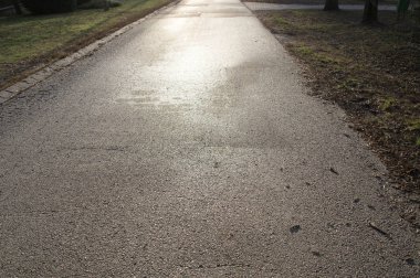 Islak asfalt yol gün batımını yansıtıyor.