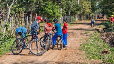 Colonia Independencia, Paraguay - 15 Ağustos 2018: Beş küçük adamlarla Paraguay'dan tipik Paraguaylı kumlu yollarından biri onların bisiklet.