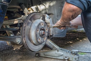 Bir arabanın fren balatalarını değiştiren bir elin yakın çekim.
