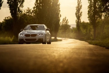 Engels, Rusya Federasyonu - 04 Haziran 2018: Beyaz araba Bmw 3 Serisi F30 günbatımında boş kırsal asfalt yolda duruyor
