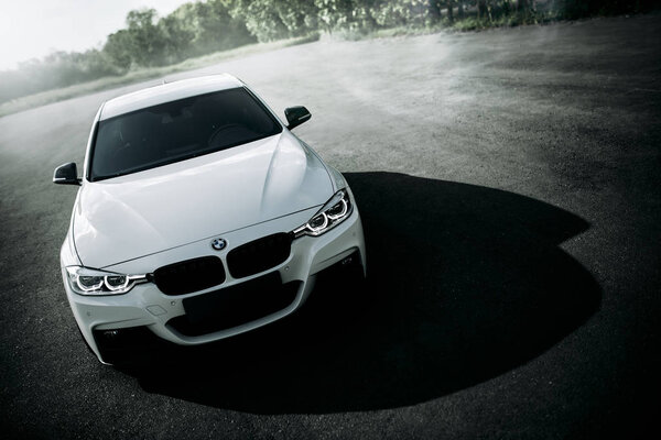 Энгельс, Россия - 04 июня 2018 года: Белый автомобиль BMW 3 серии F30 припаркован на пустой сельской асфальтовой дороге днем
