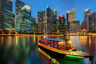 Singapur şehir manzarası. Gezi cruise gemi ve iş bölgesi görünümü. Marina Bay gece karanlığında suya yansıyan şehir merkezinde. Cityscape seyahat