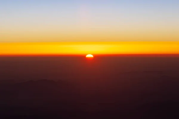 El Sol está bajando a través de la atmósfera del horizonte. Vista aérea desde la ventana del avión. Hermosa puesta de sol dorada en el cielo — Foto de Stock