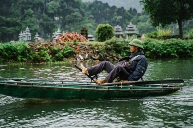 Tam Coc, Vietnam - 09 Aralık 2018: Kayıkçı Tam Coc, Ninh Binh adlı gemide yüzüyor