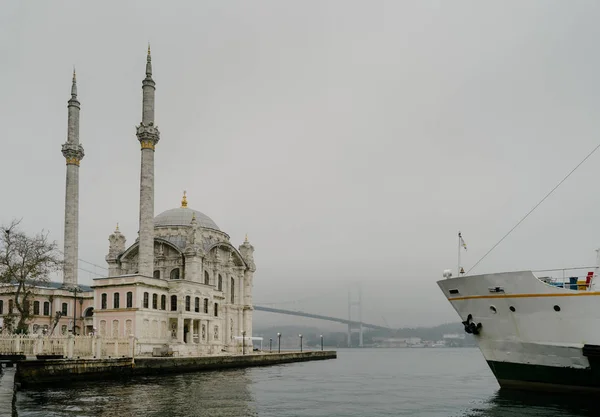 Ortakoy Mosque és Bosphorus Bridge Isztambulban, Törökországban. Drámai égbolt. A július 15-i mártírok hídja ködben — Stock Fotó