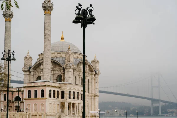 Mesquita de Ortakoy e Ponte do Bósforo em Istambul, Turquia. Céu dramático. A Ponte dos Mártires de 15 de Julho num nevoeiro — Fotografia de Stock