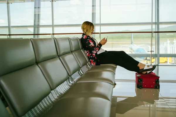 Kobieta z bagażem na lotnisku czeka na lot samolotem — Zdjęcie stockowe
