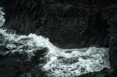 Batı İzlanda doğa manzarası. Arnarstapi köyü yakınlarındaki Snaefellsnes yarımadasındaki bazalt kaya kayalıkları. Yağmurlu havada fırtınalı dalgalar
