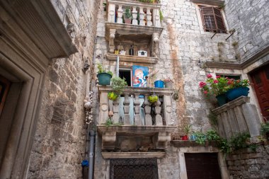 Trogir, Hırvatistan-21 Haziran 2020: Unesco dünya mirası sahasındaki güzel, renkli balkon, Trogir şehir merkezi, dar sokaklar ve meydanlarla dolu, hepsi de geleneksel yollarla beyaz, sert taşlarla yapılmış.