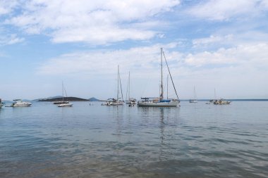 Deniz kıyısından demir atmış teknelerle kaplı Vrgada adası kumsalı, Orta Dalmaçya 'daki bu eşsiz, heyelan yaratan çevreyi ziyaret etmek için gelen turistler.                          