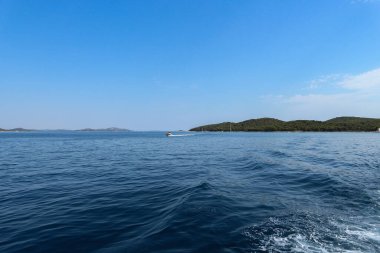 Hırvat Adriyatik Denizi 'nin açık sularında yelken açmak, Vrgada adasını uzakta bırakmak ve tekne arkasında uyanmak              