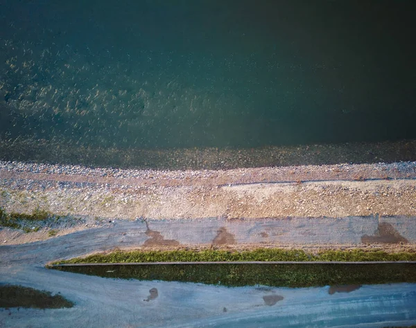 Sava nehir setinin renkli katmanları, çakıl plajı, yeşil kuşak ve asfalt yolu yakınlarda, yukarıdan insansız hava aracıyla vuruldu.