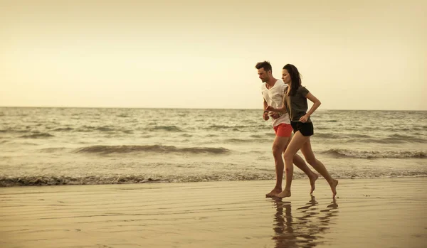 Pareja joven y atlética corriendo en la playa tropical —  Fotos de Stock