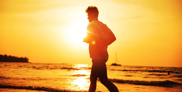 Muskulöser Mann joggt am tropischen Strand - Abendgymnastik — Stockfoto