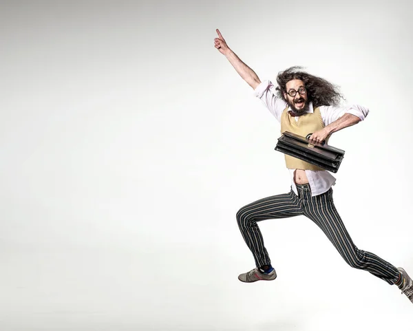 Nerdy guy holding a briefcase and jumping over the white board i — Stock Photo, Image