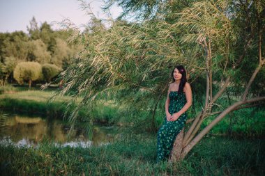 Göl kenarında çimenlerin üzerinde oturan güzel kadın