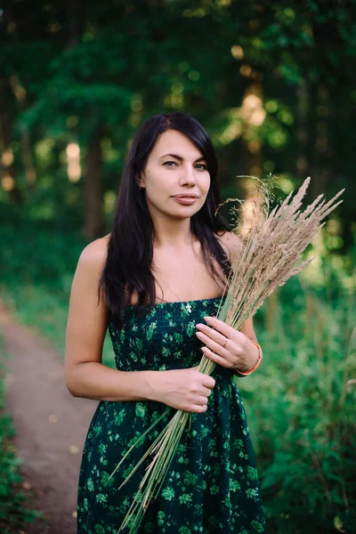 穎花の花束と森の中に立っている美しい女性 — ストック写真