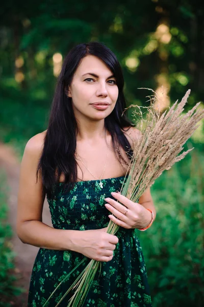 穎花の花束と森の中に立っている美しい女性 — ストック写真