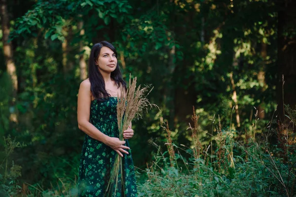 穎花の花束と森の中に立っている美しい女性 — ストック写真