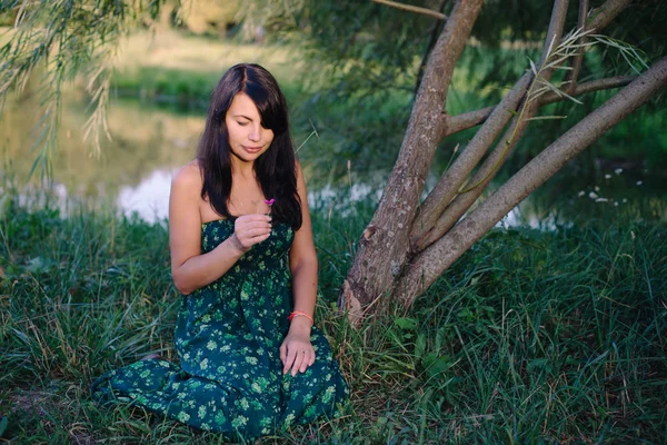 湖のそばの芝生の上に座っている美しい女性 — ストック写真