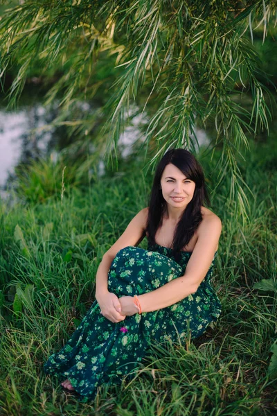 湖のそばの芝生の上に座っている美しい女性 — ストック写真
