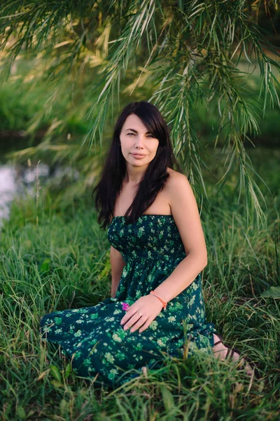 湖のそばの芝生の上に座っている美しい女性 — ストック写真