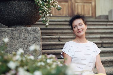 Olgun yaş güzel bir turist St Petersburg kentinde merdivenlerde oturur