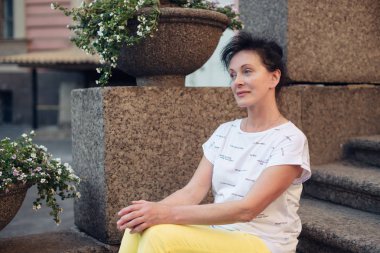 Olgun yaş güzel bir turist St Petersburg kentinde merdivenlerde oturur