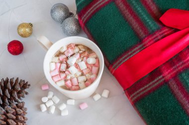 Noel içkileri. Beyaz kahve bardağı, şekerleme ve tarçın, sıcak ekose, kozalak, beyaz mermer arka planda Noel topları. Kış zamanı. Yukarıdan bak. Noel tatili kavramı