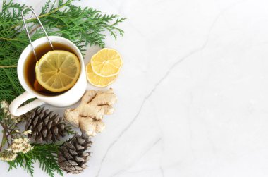 Noel 'de, Şükran Günü' nde içeceğiz. Limonlu çay ve zencefil. Sonbahar, kış içkisi, sıcak çay, sıcak şarap. Noel ağacı dalları ve koniler. Beyaz mermer arka planda. Yukarıdan bak. Boşluğu kopyala