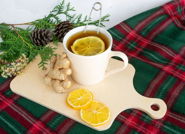 Drinks for Christmas, Thanksgiving. Tea with lemon and ginger. Autumn, winter drink, hot tea, mulled wine. Christmas tree branches, a cozy blanket. On a white marble table close-up. Delicious traditional hot drink