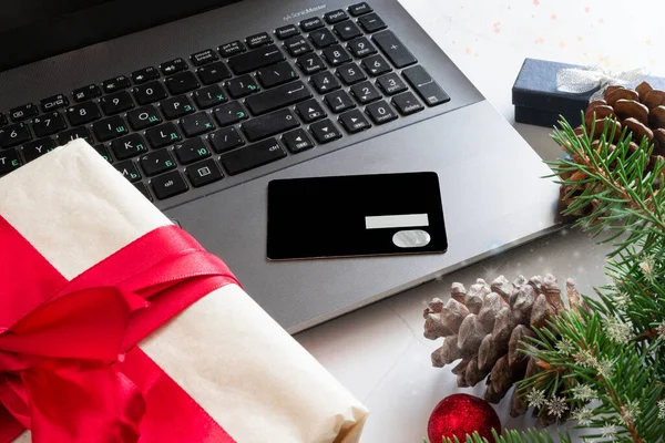 Noel tatili için internetten kredi kartı ve dizüstü bilgisayarla Noel alışverişi. Kara Cuma. Noel süsleri, hediyeler, defter, beyaz mermer zemin.