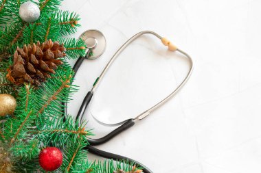 Yılbaşı doktoru. Noel 'i sağlık hizmetlerinde kutluyoruz. Düz manzaralı. Beyaz mermer arka planda steteskop. Hediye kutusu, kopyalama alanı ve afişi olan tıbbi Noel kartı