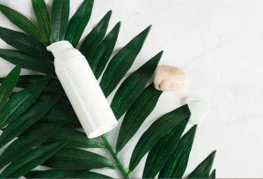 Kavanozda beyaz krema. Tropik yapraklar, spa konsepti. Beyaz mermer bir arkaplan görünümünde