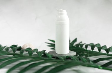 Kavanozda beyaz krema. Tropik yapraklar, spa konsepti. Beyaz mermer bir arka planda