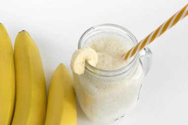 Cam bir kavanozda muzlu taze meyve püresi, muzların yanında, hafif bir arka planda. Sağlıklı yiyecekler. Spor beslenmesi. Yukarıdan bak. Seçici odak.