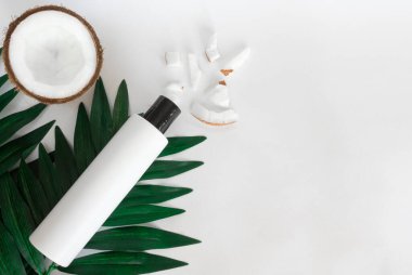 Hindistan cevizi saç şampuanı, hindistan cevizi parçaları, palmiye yaprağı ve beyaz arka planda taze hindistan cevizi. Cilt bakımı konsepti, sertlik ve gençlik. Yukarıdan bak. Boşluğu kopyala