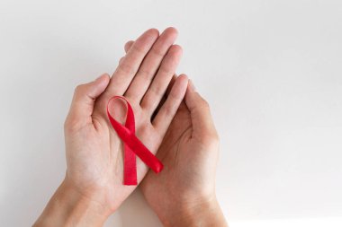 Sağlık ve tıp konsepti - kırmızı AIDS farkındalığı kurdelesi tutan kadın elleri. Beyaz arkaplanda uluslararası yardım günü.