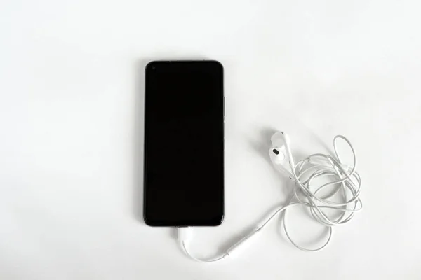 Karışık kulaklıklar ve beyaz arka planda akıllı telefon. Yukarıdan bak. Uzayı kopyala Müzik konsepti