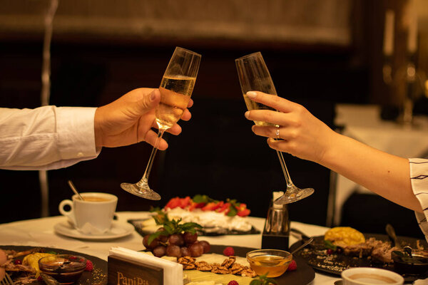 Loving couple with spampans in hands in a restaurant. engagement ring