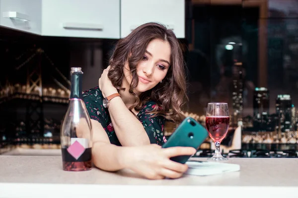 The young lady alone drinks champagne and looks on the phone