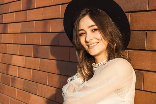 Tuğla arka planda şapkası olan bayan.