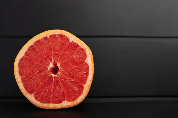 Siyah arkaplanda bir dilim greyfurt.